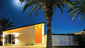 A modern house with a garage, a well-lit entrance, and a palm tree in the yard.