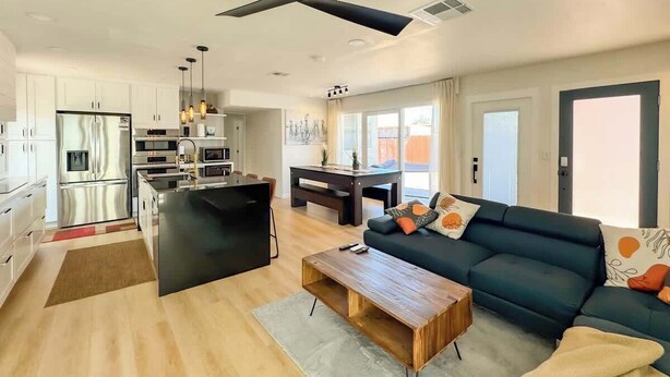 A modern living space with a kitchen, dining area, and a sofa with cushions.