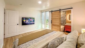 A bedroom with a bed, a TV, a sliding door, a red dresser, and a window.