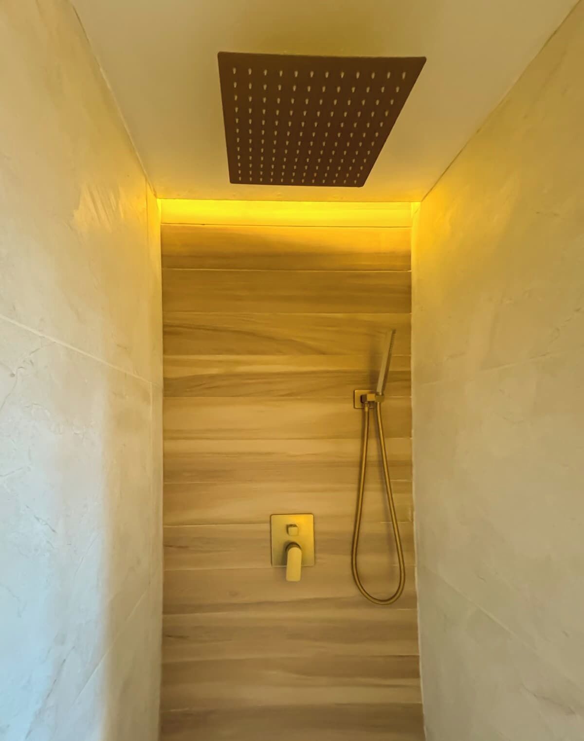 A shower with a wooden panel wall and a handheld showerhead.