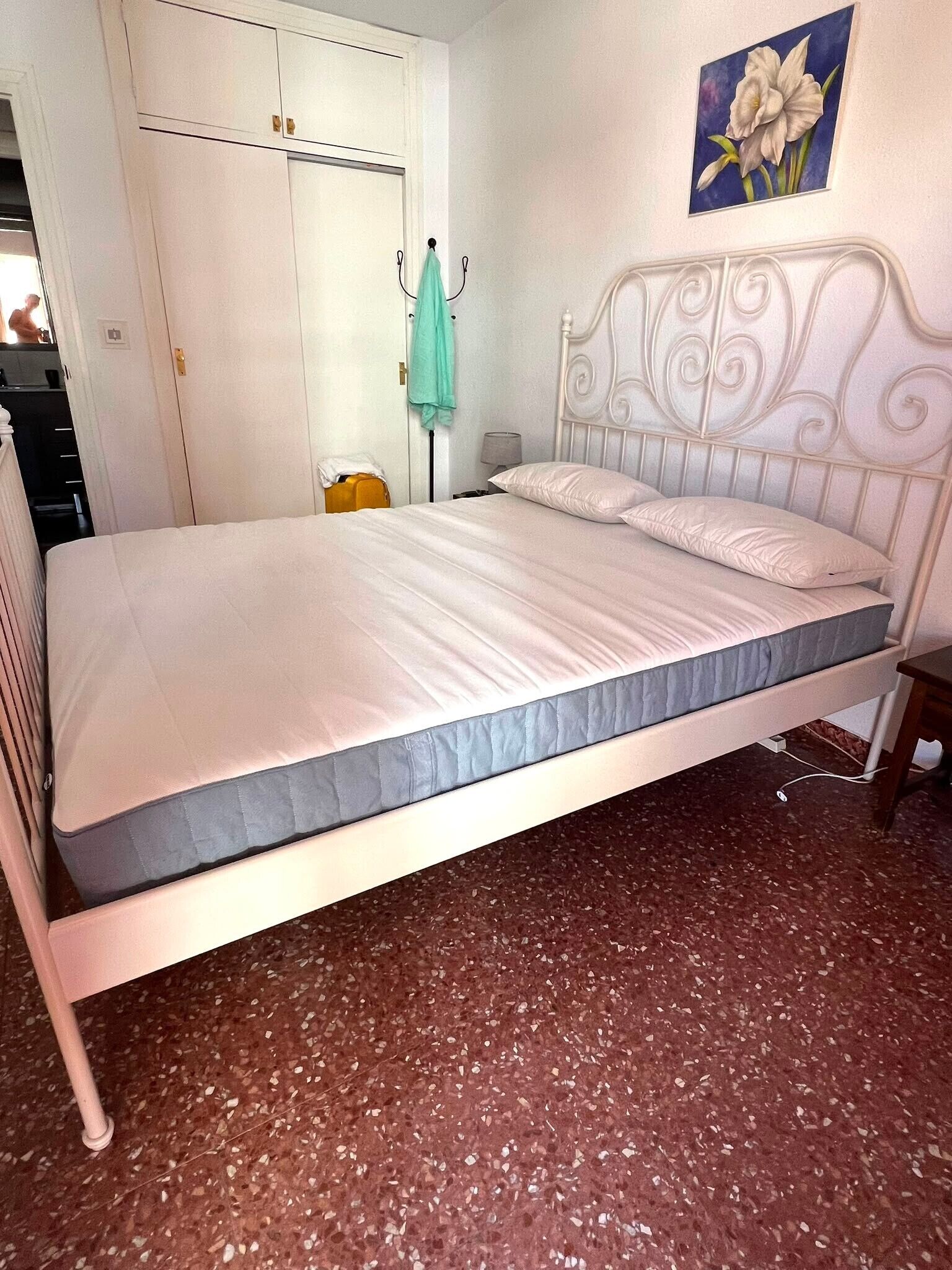 A single bed with a headboard, a small bedside table, and a wall-mounted lamp.