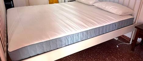 A single bed with a headboard, a small bedside table, and a wall-mounted lamp.