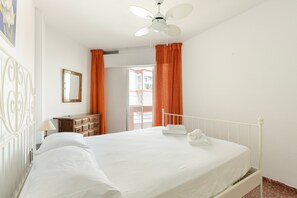 Ein Hotelzimmer mit Bett, Schminktisch, Spiegel und Deckenventilator.
