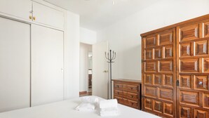 Hotellihuone, jossa on sänky, puinen vaatekaappi ja naulakko.