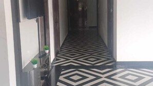 Un couloir doté d’un sol à motifs géométriques, un téléviseur à écran plat fixé au mur et un comptoir d’accueil agrémenté d’une plante en pot.