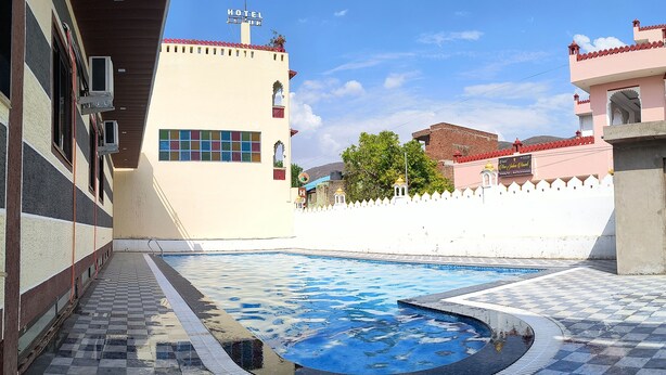 Un hôtel doté d’une piscine, d’un sol à carreaux et d’une clôture blanche.