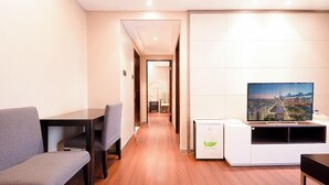 A modern living room with a flat-screen TV, a dining table, and a sofa. - Tianxi Apartment KKone Branch (Shenzhen)