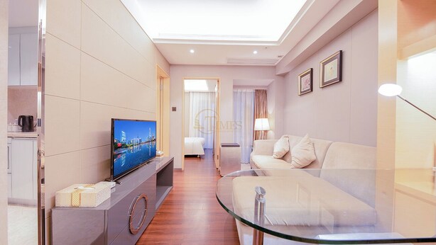A modern hotel room with a flat-screen TV, a sofa, a glass coffee table, and a bed. - Tianxi Apartment KKone Branch (Shenzhen)