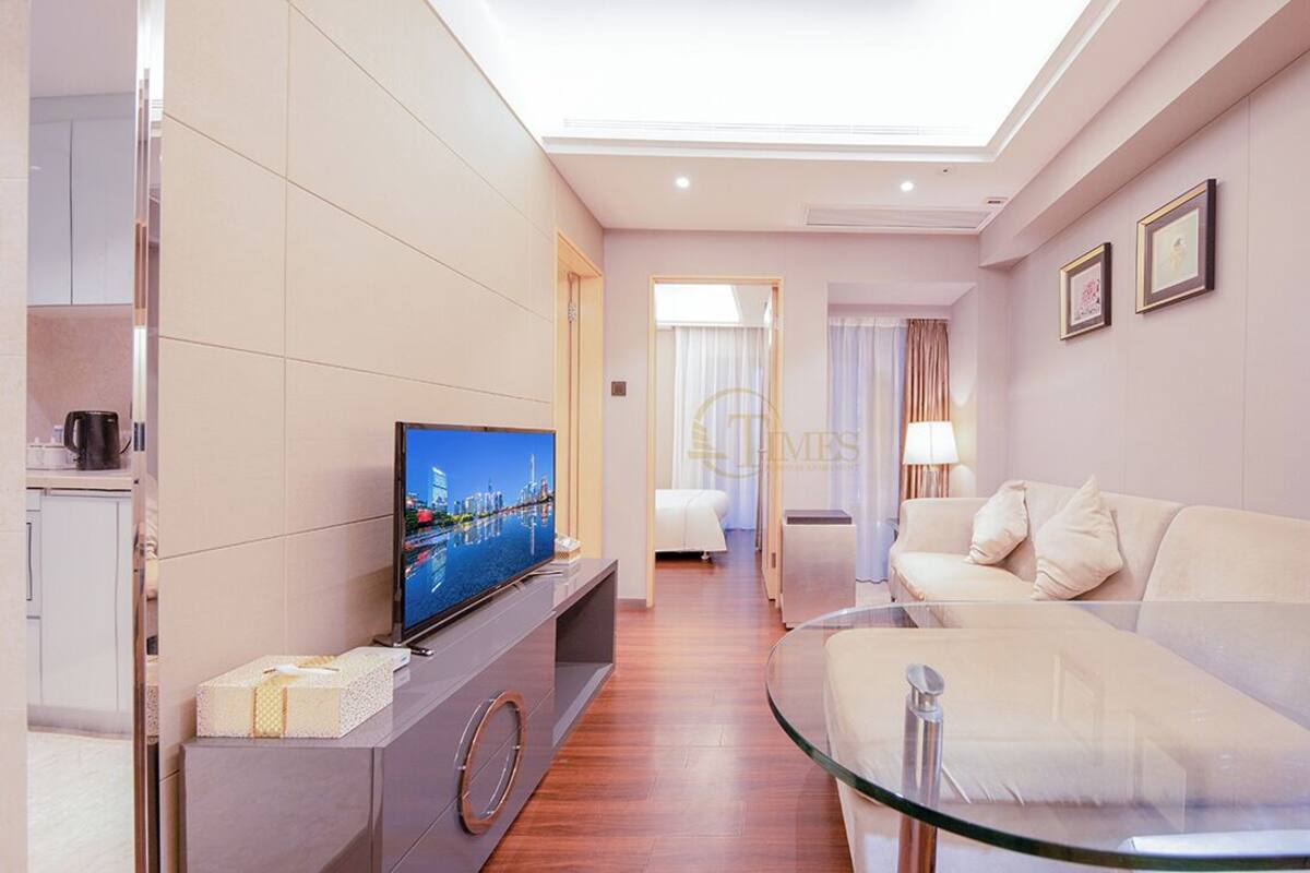 Una habitación de hotel moderna con televisión de pantalla plana, un sofá, una mesa de centro de vidrio y una cama.