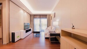 A modern hotel room with a flat-screen TV, a sofa, a desk, and a large window with curtains. - Tianxi Apartment KKone Branch (Shenzhen)
