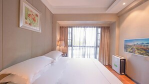 A hotel room with a large bed, a nightstand, a lamp, a radiator, and a cityscape painting on the wall. - Tianxi Apartment KKone Branch (Shenzhen)