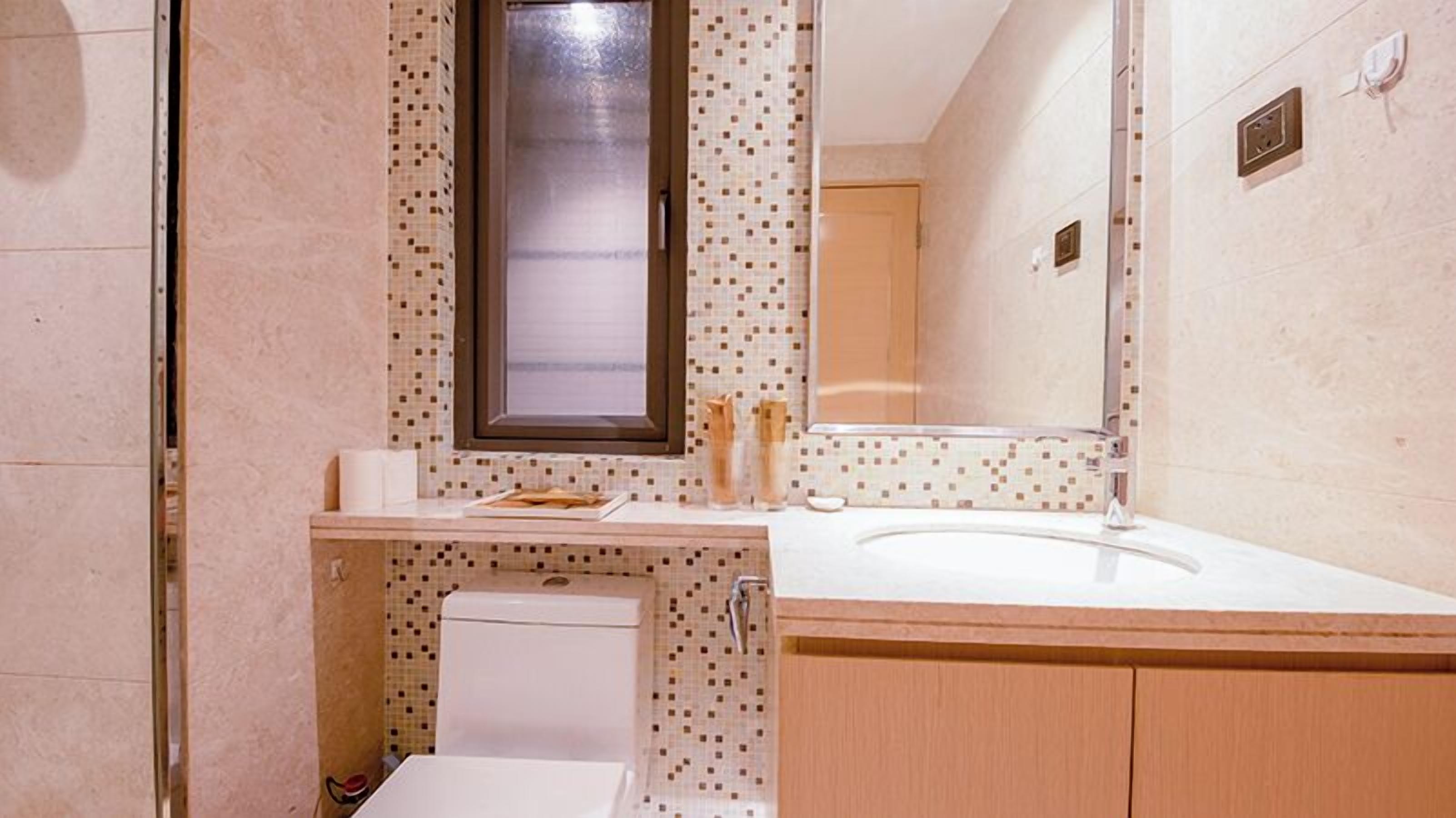 A small bathroom with a toilet, sink, and mirror.