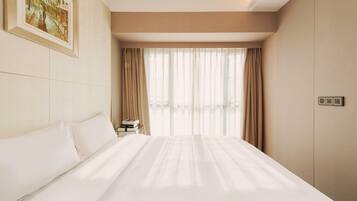 A hotel room with a large bed, a nightstand, a painting on the wall, and a window with curtains.