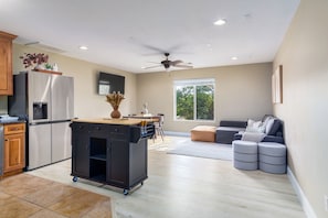 A modern kitchen with a refrigerator, stove, and a cart. There is a dining area with a table and chairs, and a seating area with ottomans. - Zion hidden Oasis (Hurricane)