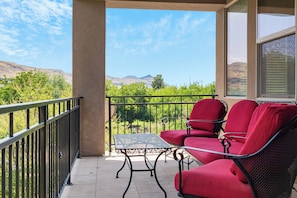 A balcony with a table and two red chairs, overlooking a mountainous landscape. - Zion hidden Oasis (Hurricane)