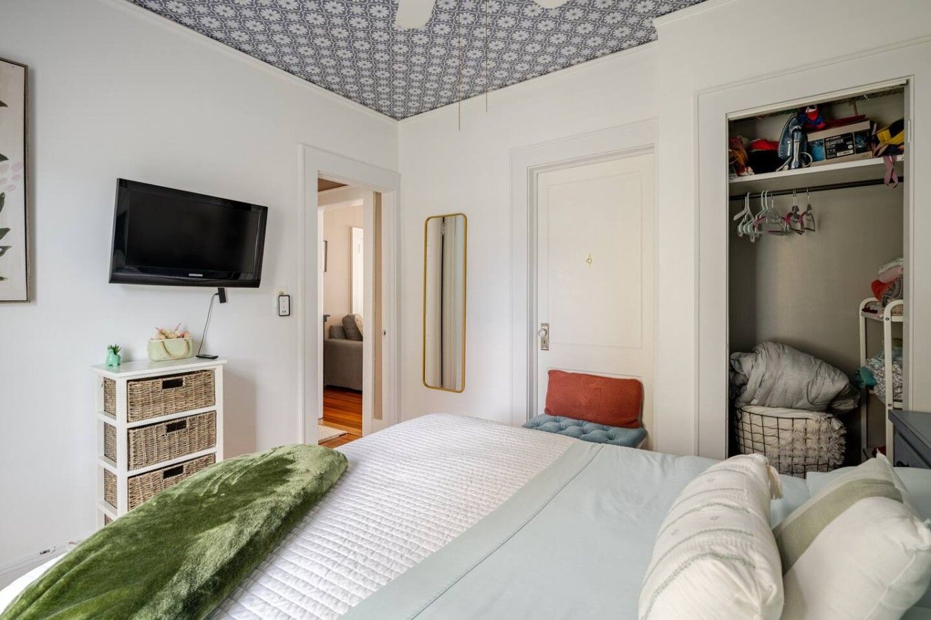 A bedroom with a bed, a television, a wardrobe, and a mirror.