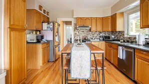 Una cocina moderna con armarios de madera, electrodomésticos de acero inoxidable y una isla central con taburetes.