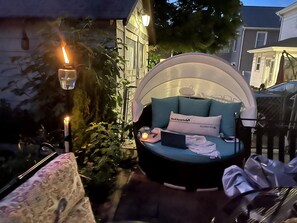 Een terras met een ronde tafel, een stoel en een hanglamp.