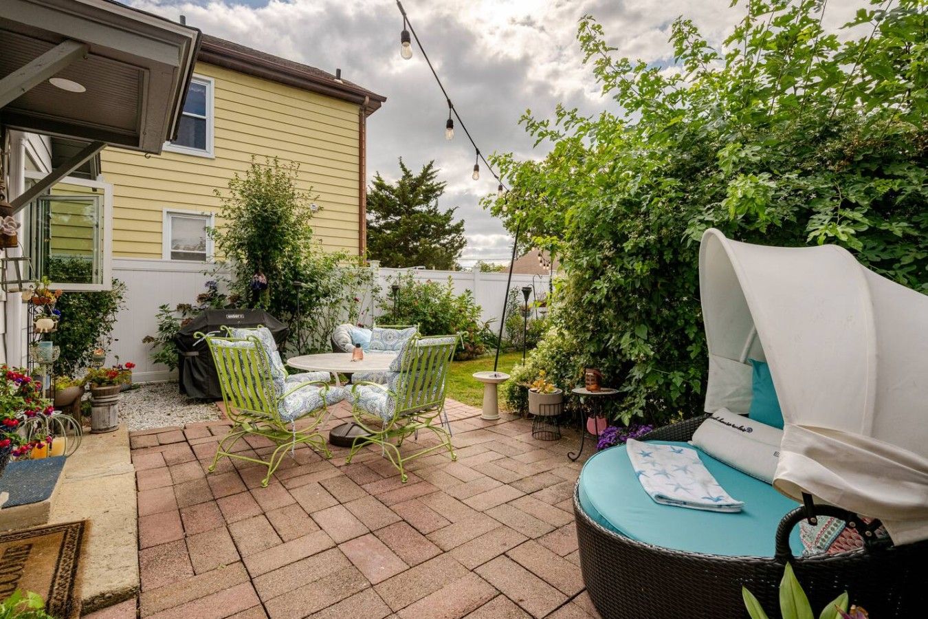 A patio with outdoor furniture, a grill, and potted plants.