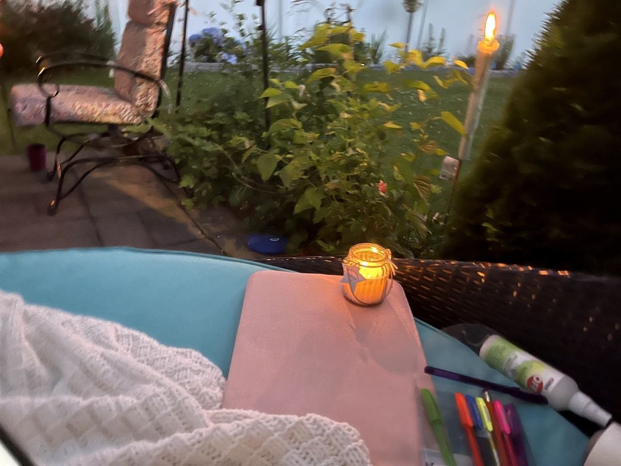 A table with a candle, a notebook, and pens.