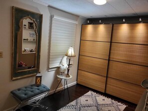 Une pièce avec un grand miroir, une lampe, un banc bleu rembourré et un tapis à motifs.