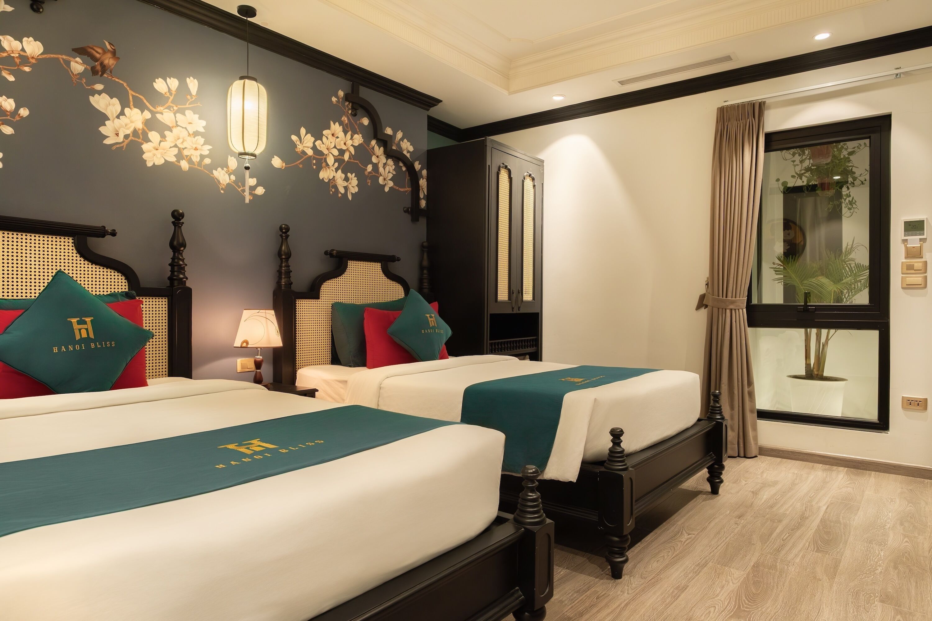 Een hotelkamer met twee bedden, een groot raam met uitzicht en een decoratieve wand met bloemenmotieven.