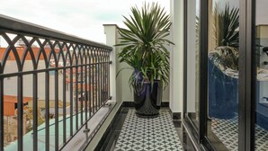A balcony with a potted plant, patterned floor tiles, and a metal railing. - Bliss Signature Hotel (Hanoi)