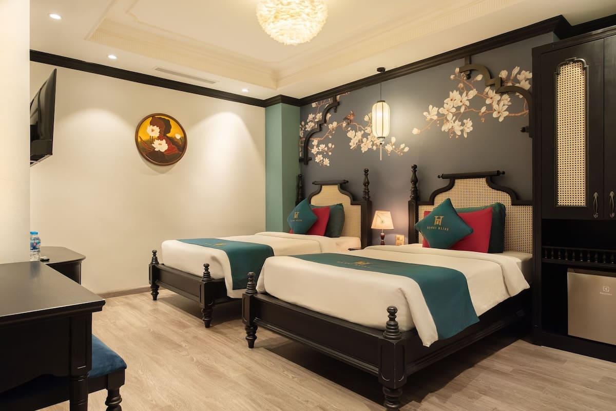 A hotel room with two beds, a desk, and a television.