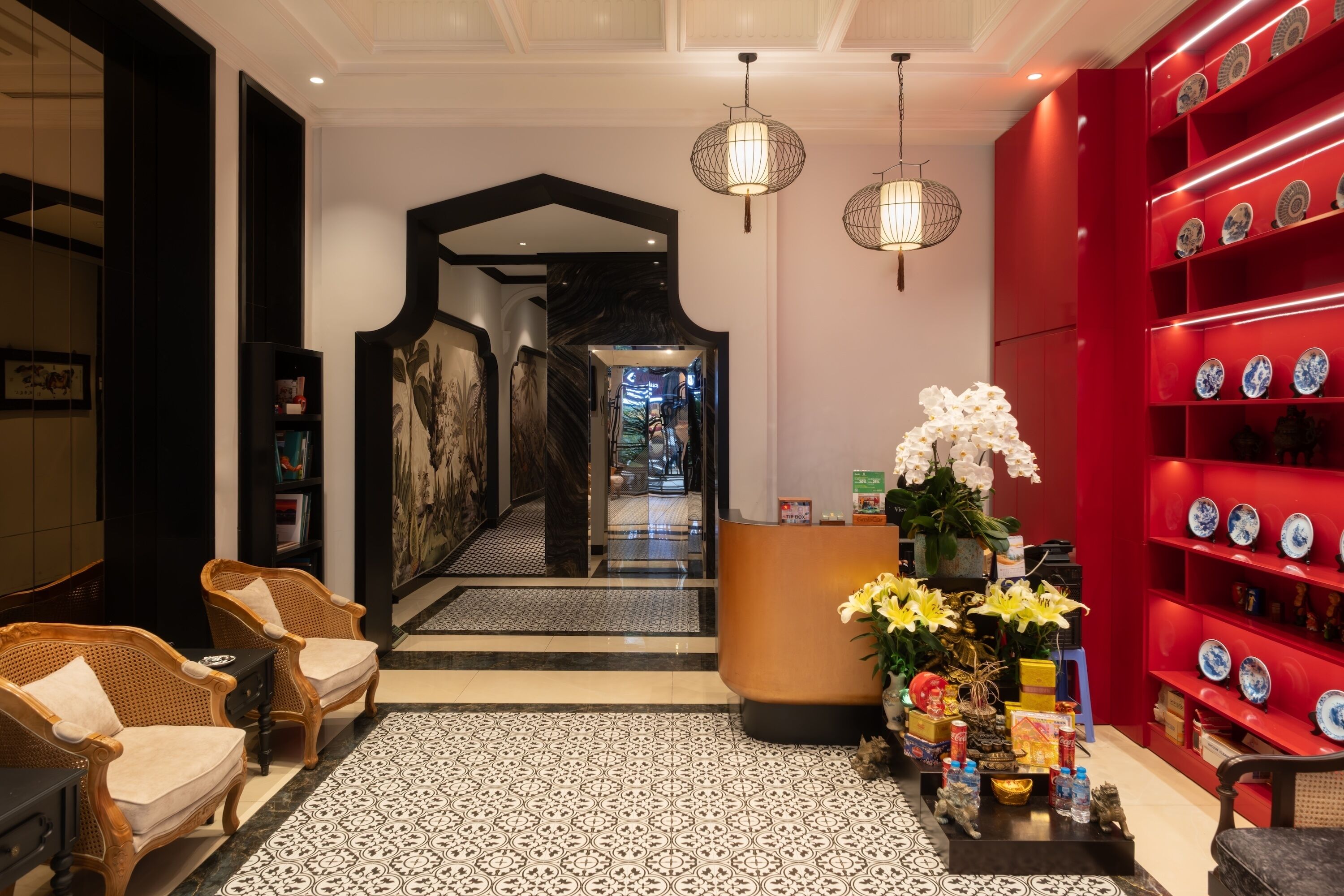 A hotel lobby with a reception desk, seating area, and a red display of decorative plates.