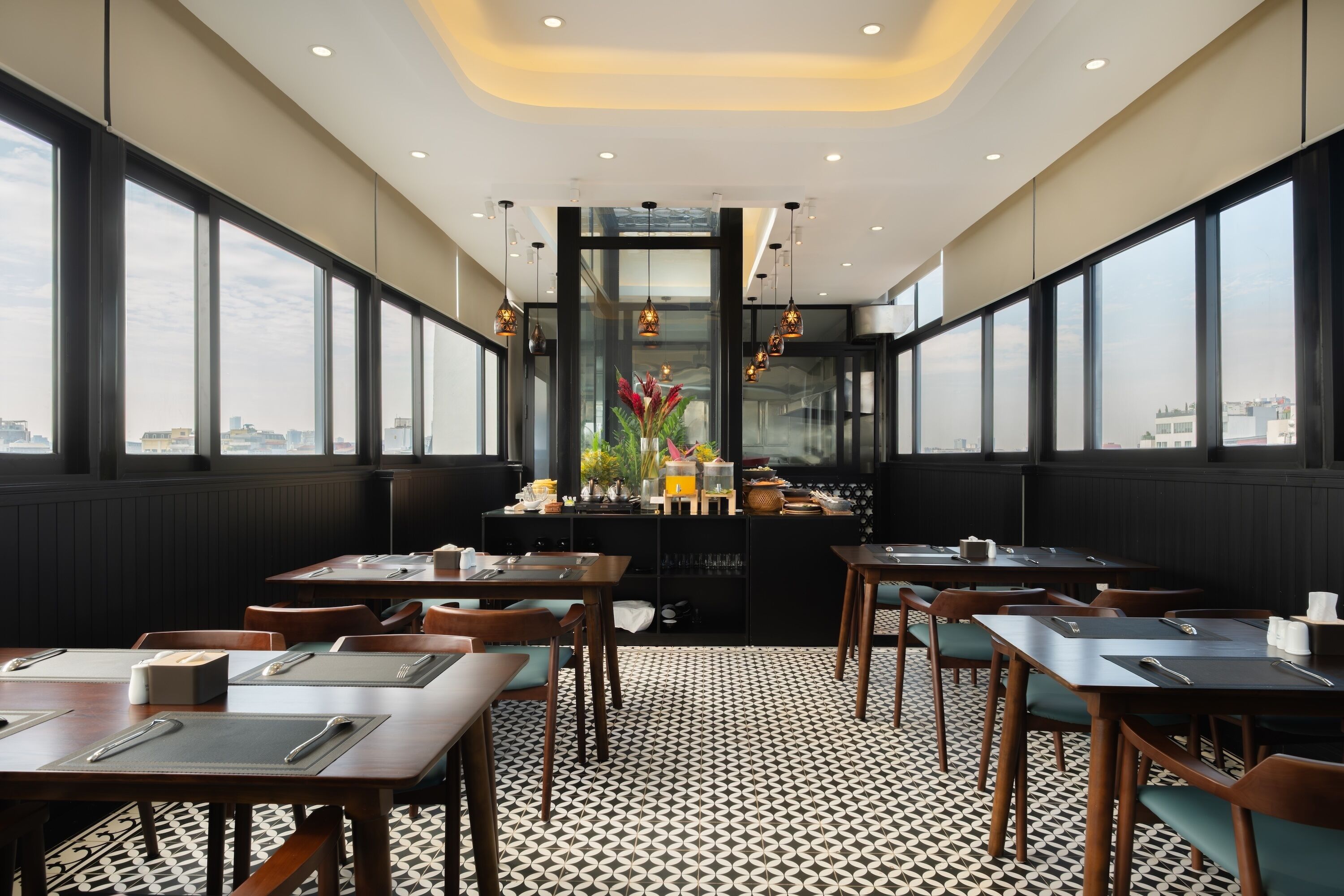 En restaurang med en modern inredning, med ett svart- och vitrutigt golv, träbord och stolar samt stora fönster med utsikt över staden.