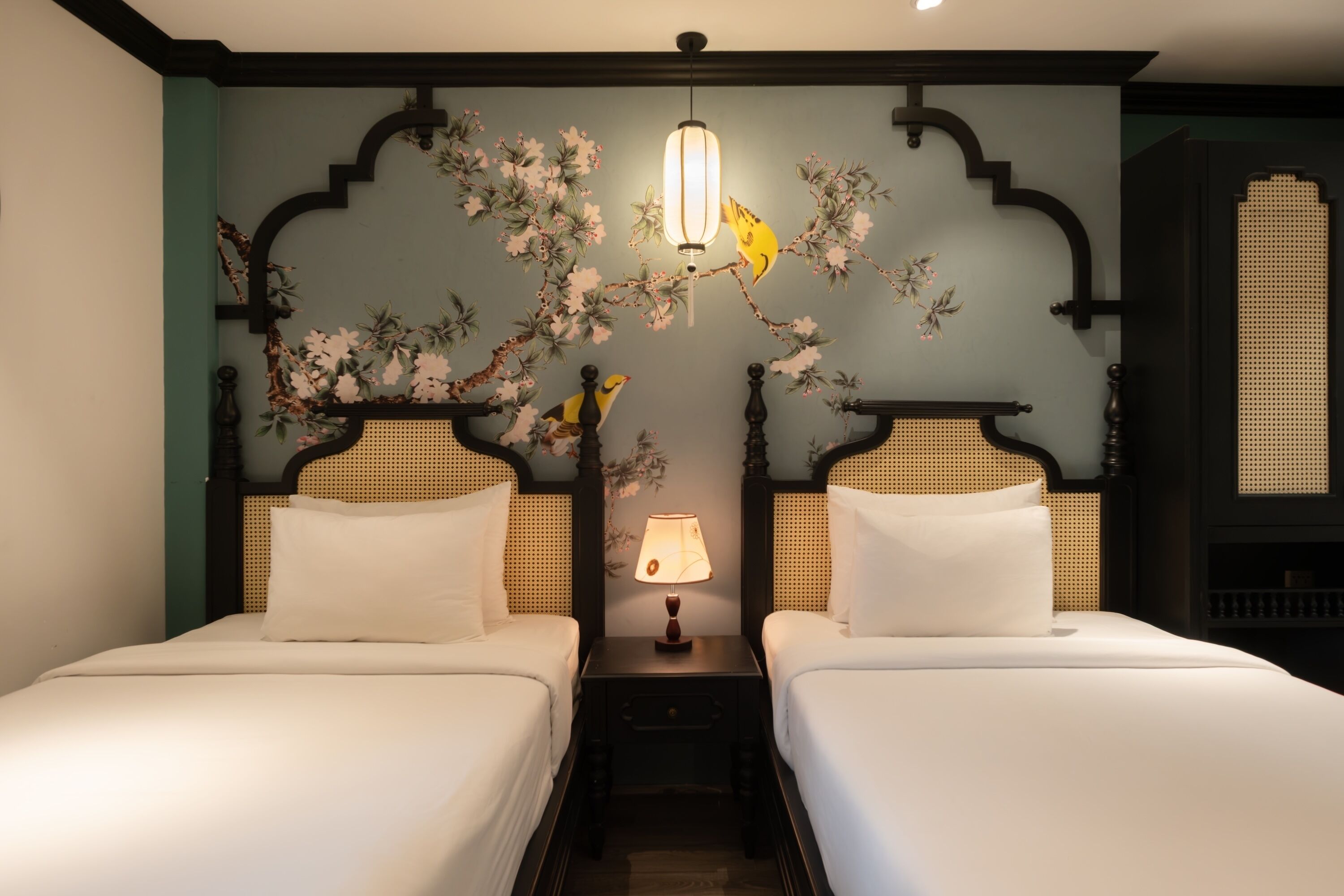 Habitación de hotel con dos camas, una mesita de noche con lámpara y decoración en la pared.