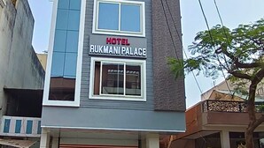 Un hôtel à plusieurs étages, nommé «Hôtel Rukmani Palace», doté d’une façade moderne, de grandes fenêtres et d’une entrée de garage bien visible.