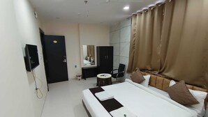 Une chambre d’hôtel avec un grand lit, un bureau, une chaise, une télévision et un miroir.