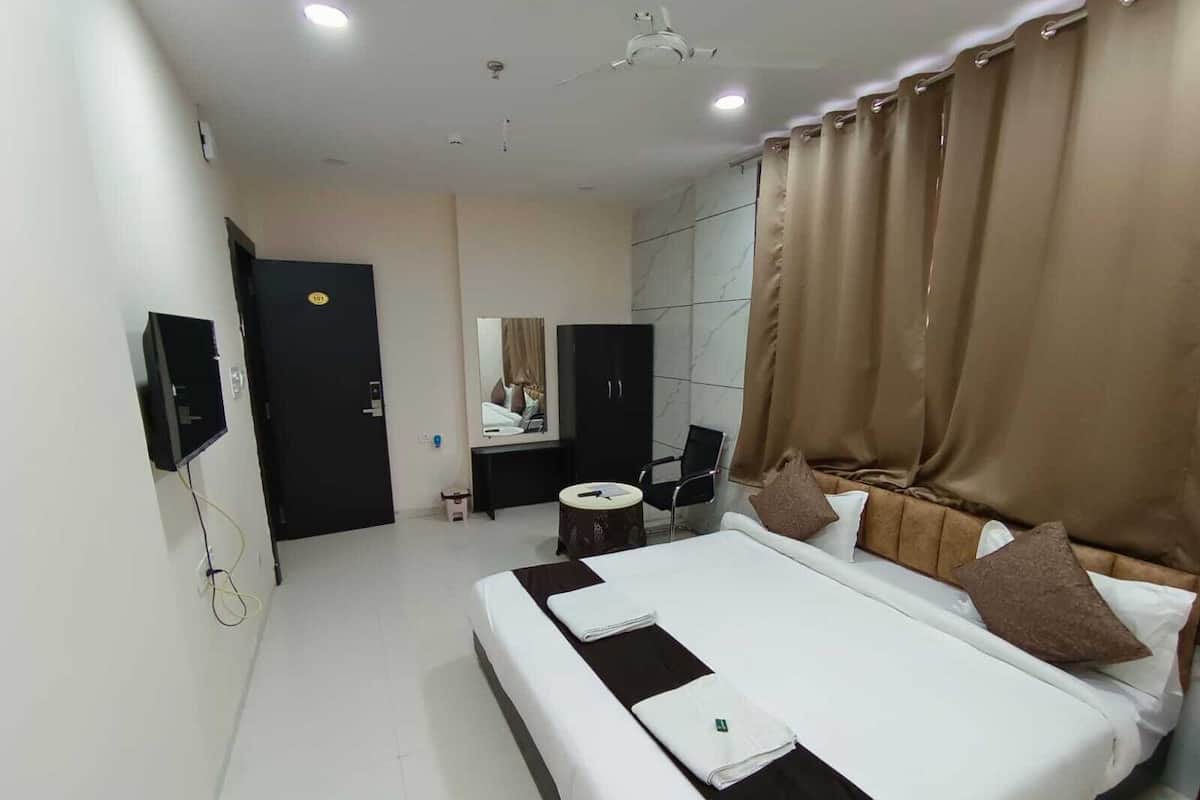 Une chambre d’hôtel avec un grand lit, un bureau, une chaise, une télévision et un miroir.