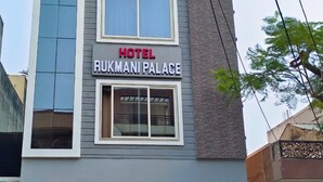 Un hôtel appelé « Hotel Rukmani Palace », doté d’une façade moderne, de deux fenêtres bien visibles et d’une entrée de garage.