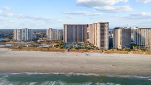 Ein Strandhotel mit mehreren Hochhäusern, einem Sandstrand und blauem Himmel.