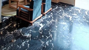 A room with a wooden ceiling, a black and white marble floor, a sofa, and a small table with a plant. - Hotel Nayra Manali (Manali)
