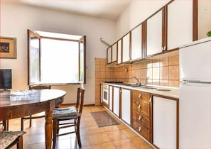 A kitchen with wooden cabinets, a white refrigerator, and a dining table with chairs.