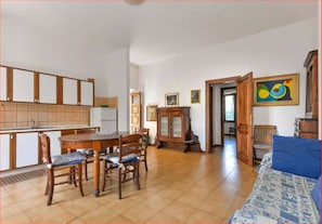 A spacious living area with a dining table and chairs, a sofa, and a wooden cabinet.