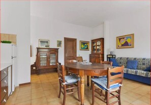 Un comedor con una mesa y sillas de madera, un armario y un sofá.