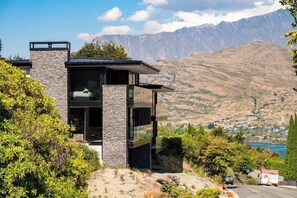 A modern two-story building with a stone facade, large windows, and a view of a mountainous landscape.