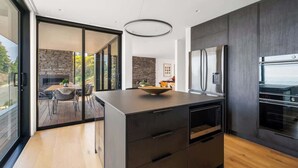 Una cocina moderna con una isla grande, electrodomésticos integrados y vistas a un patio exterior a través de puertas de vidrio.