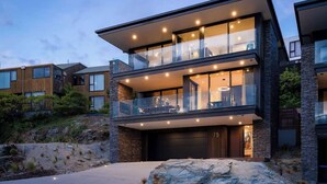 Una casa moderna de dos pisos con garaje, ventanas amplias y un balcón.