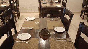 A dining area with a long wooden table set for multiple people, surrounded by chairs. - Five Elements Hotel Haridwar (Haridwar)