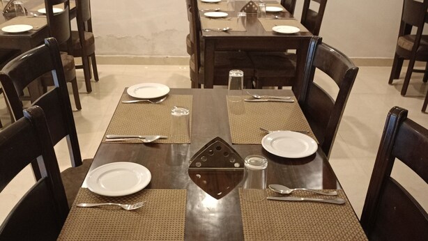 A dining area with a long wooden table set for multiple people, surrounded by chairs. - Five Elements Hotel Haridwar (Haridwar)