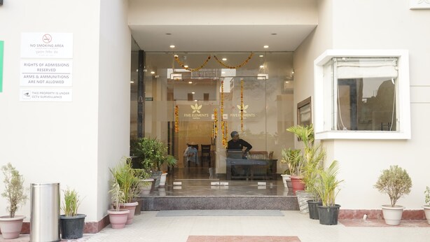 A hotel entrance with a glass door, potted plants, and a sign indicating no smoking and CCTV surveillance. - Five Elements Hotel Haridwar (Haridwar)