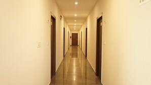 A long, narrow hallway with doors on both sides, leading to a central door at the end. - Five Elements Hotel Haridwar (Haridwar)