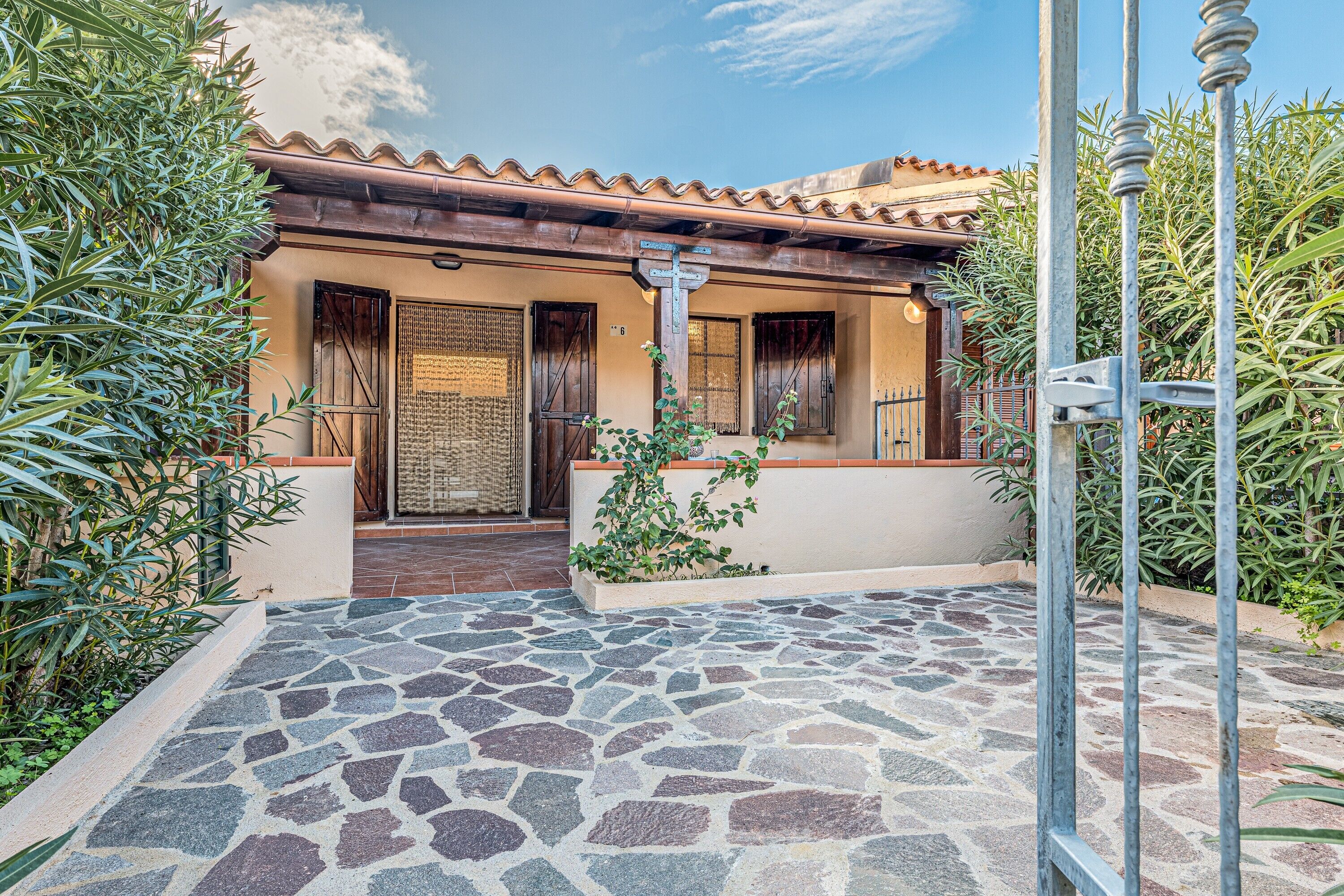 A building with a tiled roof, a stone-paved entrance, and a metal gate.