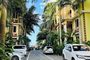 Stroll along a picturesque street lined with multi-story buildings featuring balconies and lush palm trees.