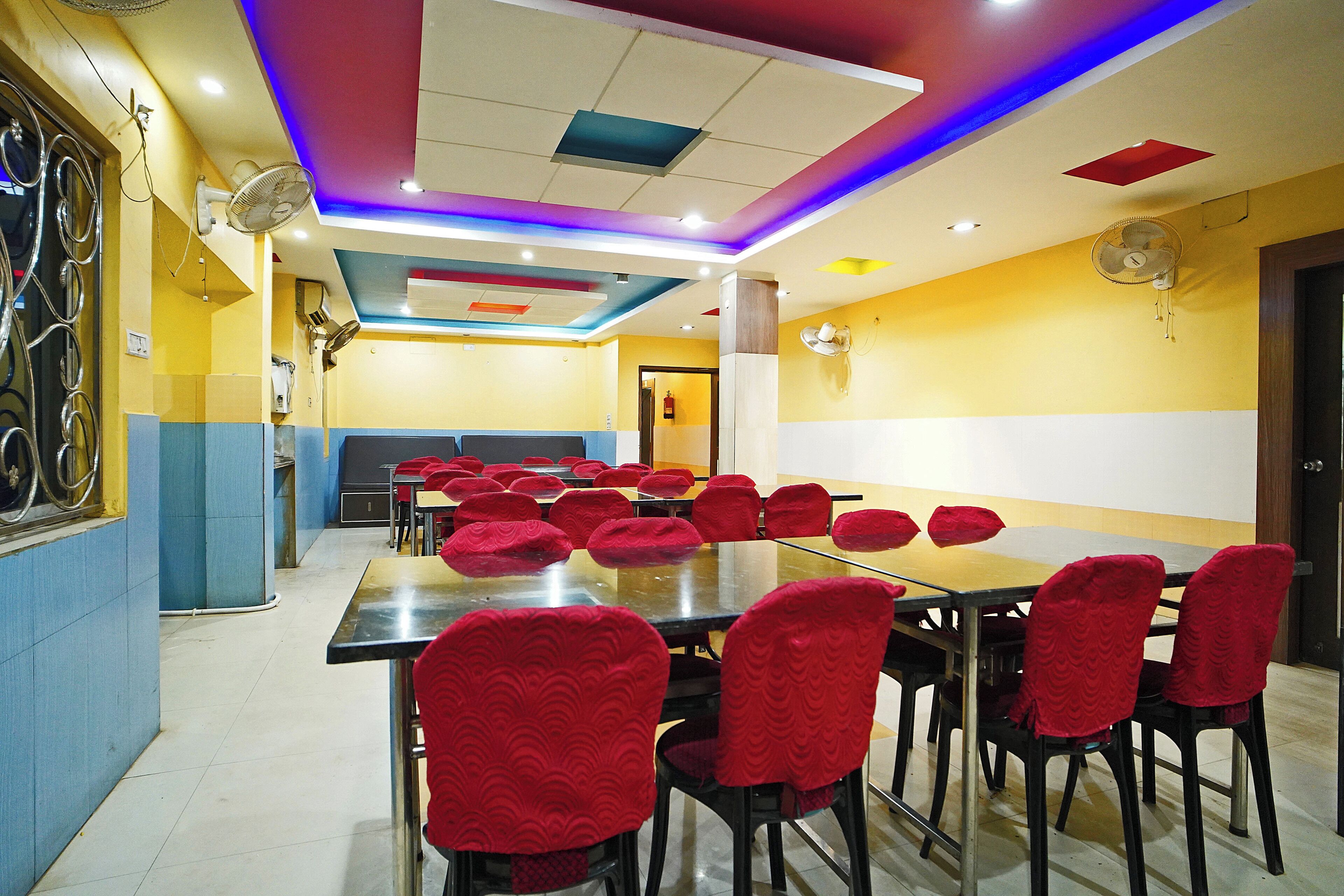A conference room with a long table and red upholstered chairs, equipped with ceiling fans and recessed lighting.